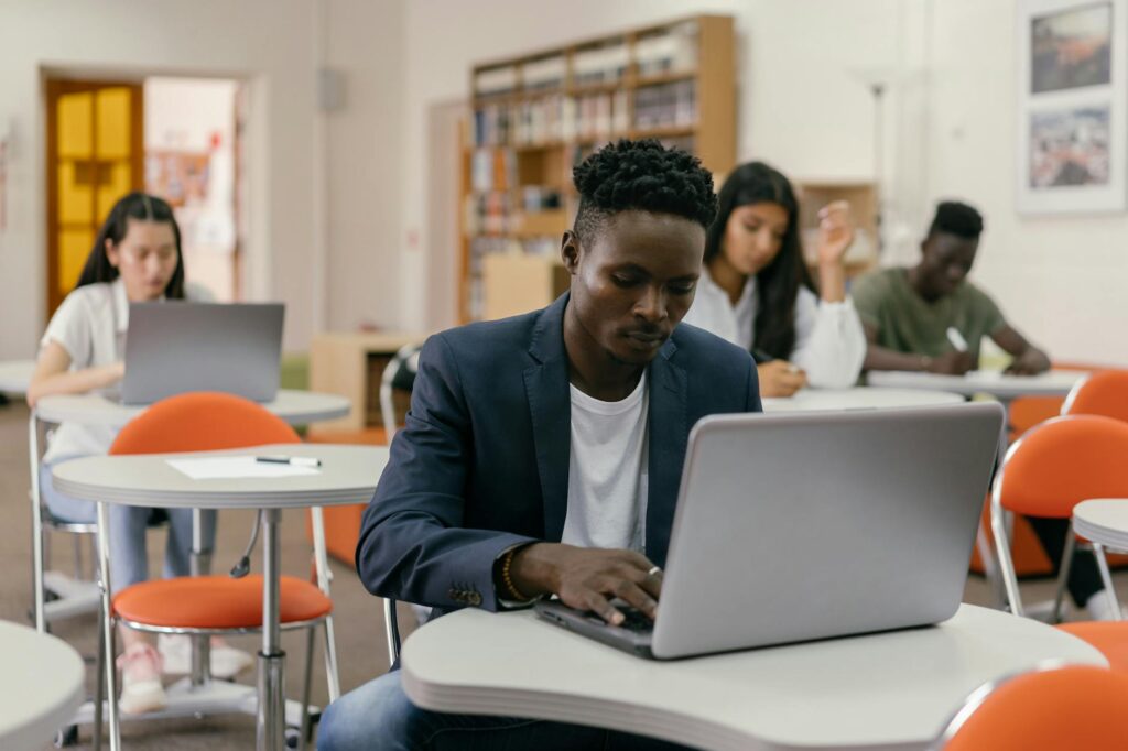 college student smiling while filling out scholarship application on laptop at desk
