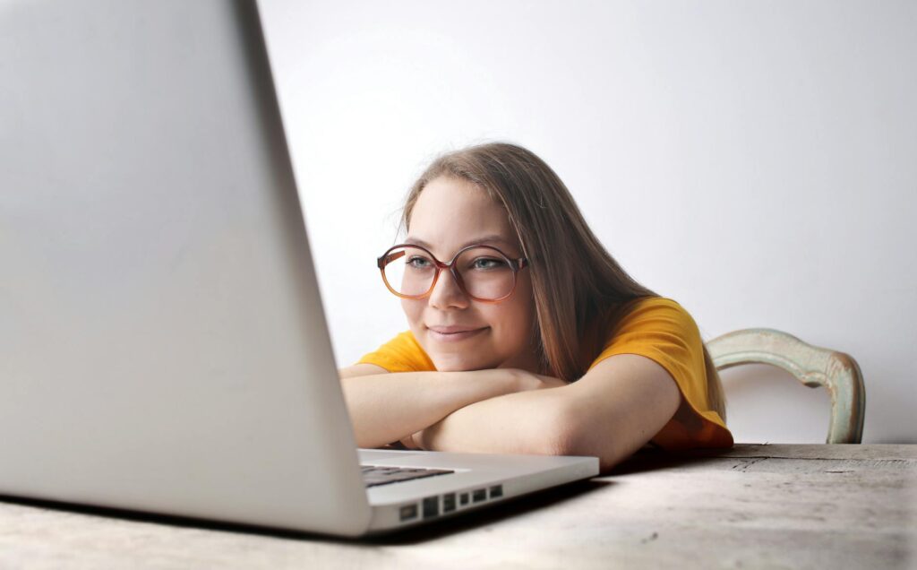 college student smiling while filling out online scholarship application on laptop