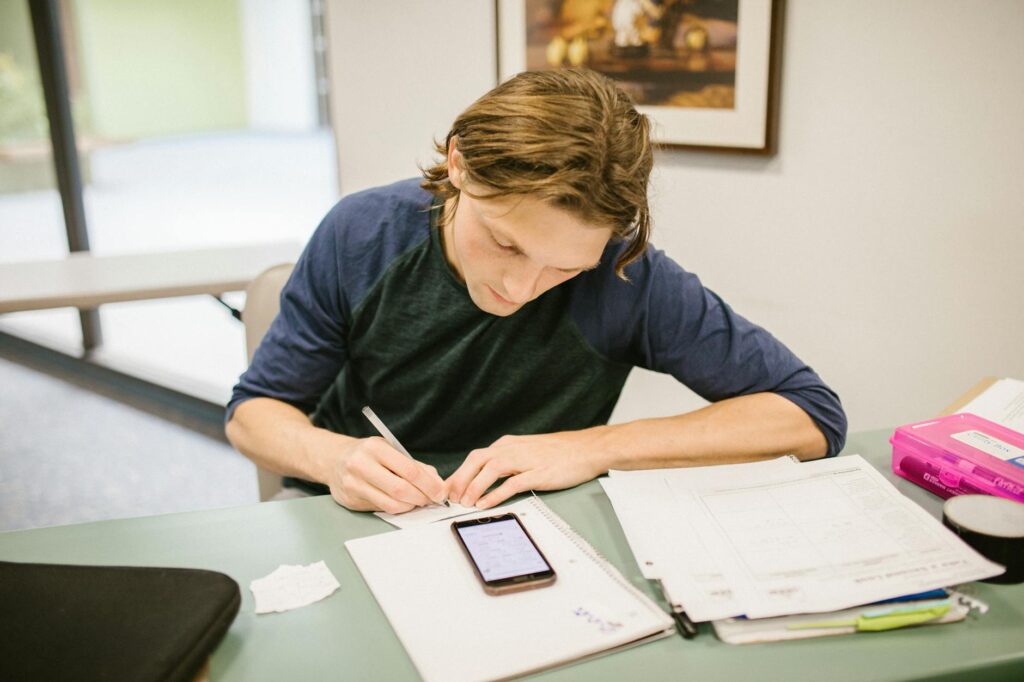 college student smiling while reviewing financial aid paperwork at a desk