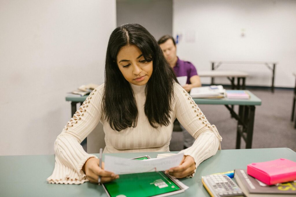 college student smiling while reviewing financial aid documents at a desk