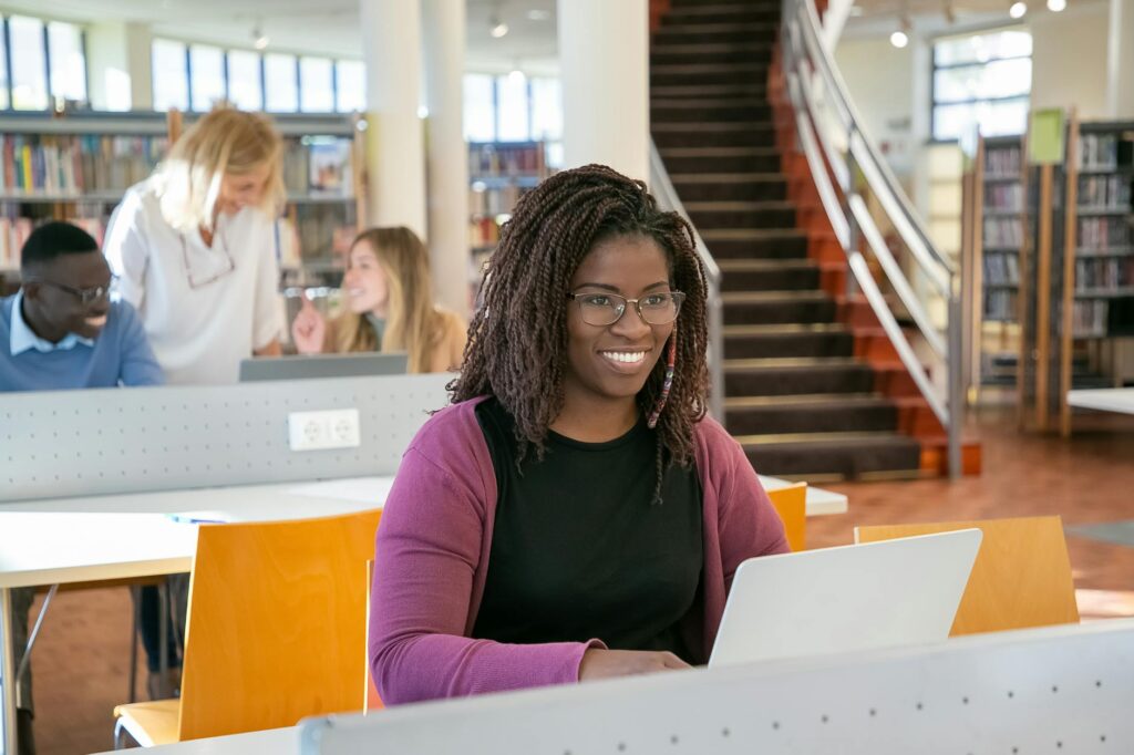 community college student smiling while filling out scholarship application on laptop