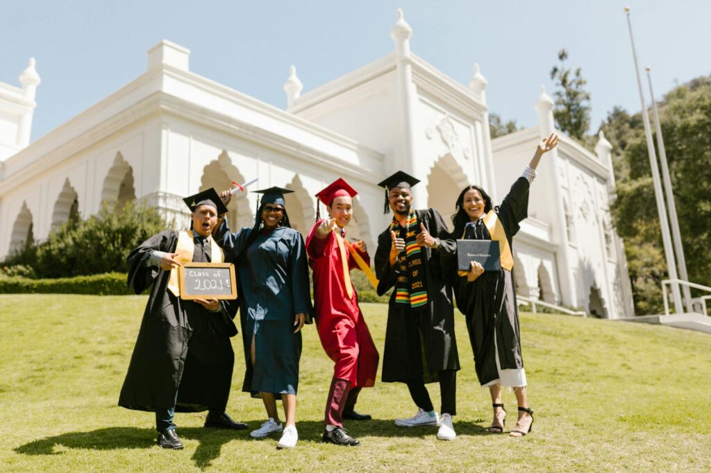 diverse group of women in caps and gowns celebrating graduation outdoors