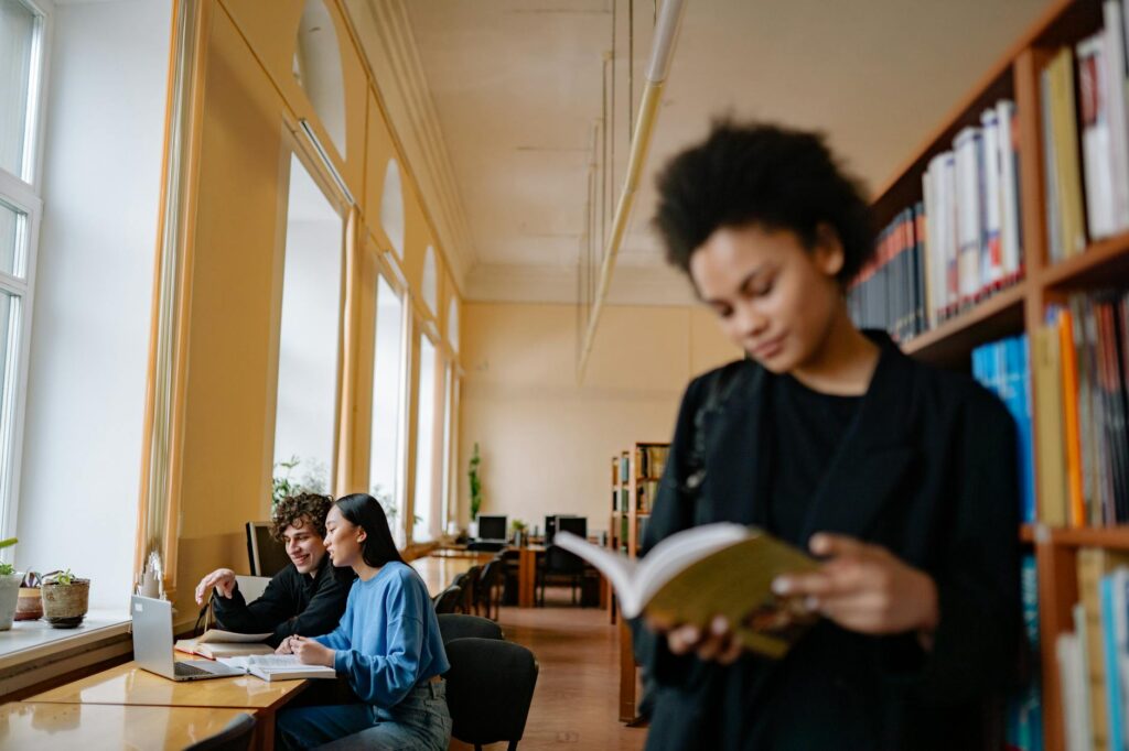international students studying together on university campus with books and laptops