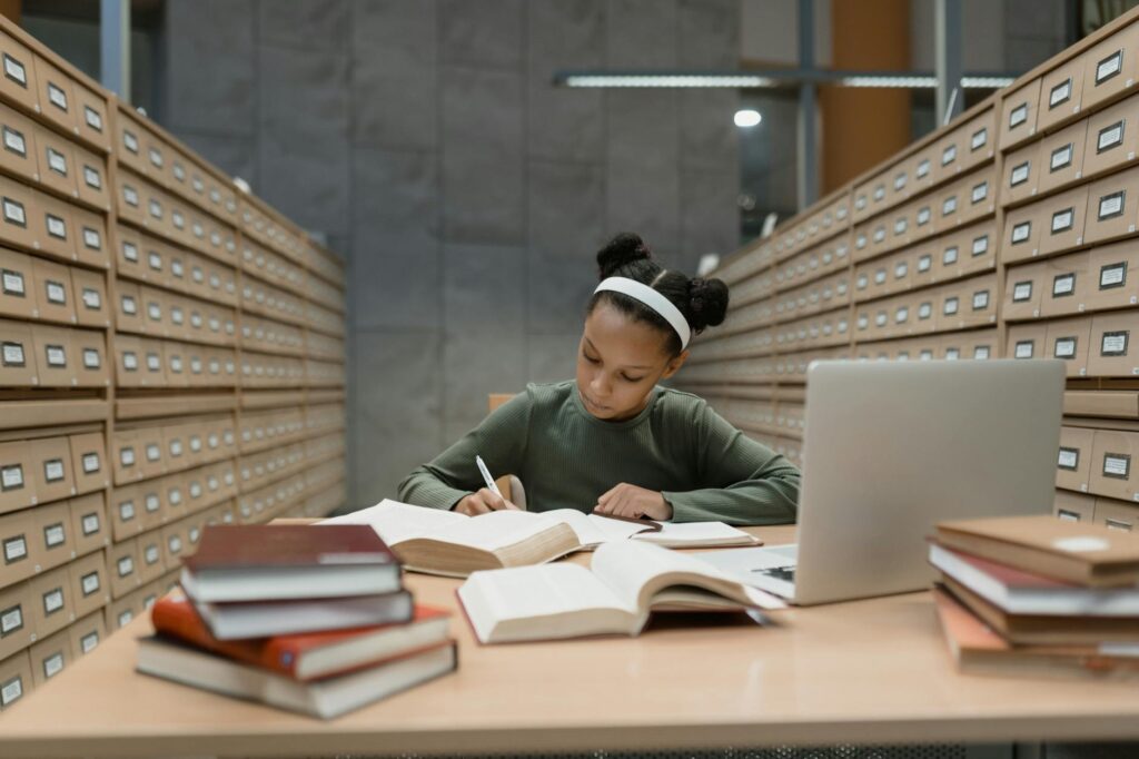 minority student writing scholarship essay at desk with laptop