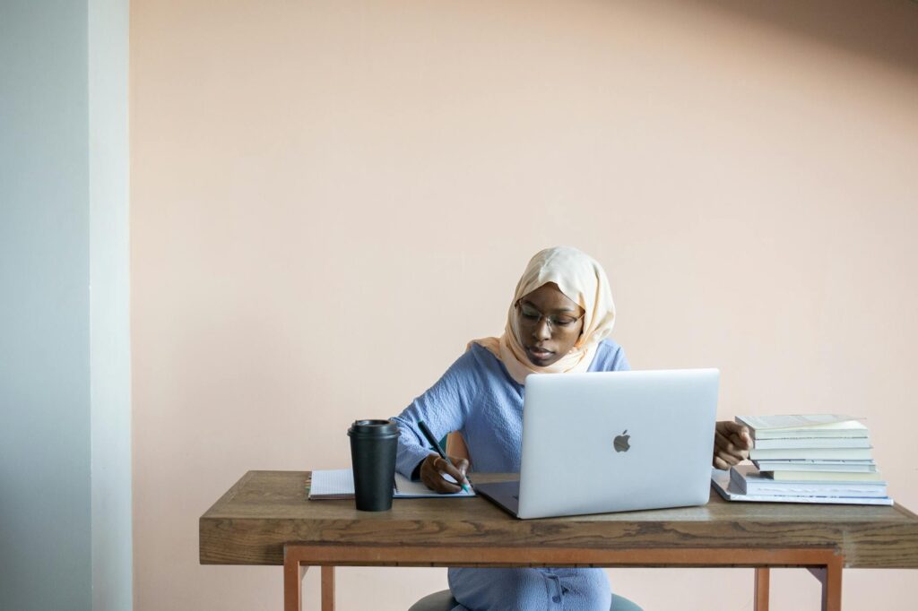 Nigerian university student smiling while filling out scholarship application on laptop