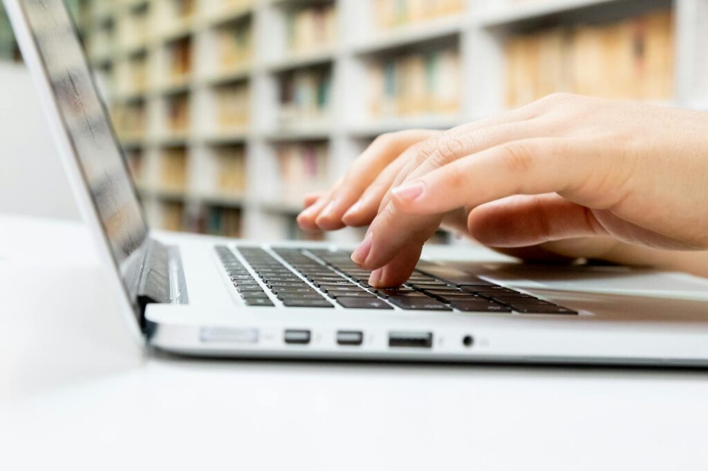 student searching scholarship databases on laptop at library with coffee cup nearby