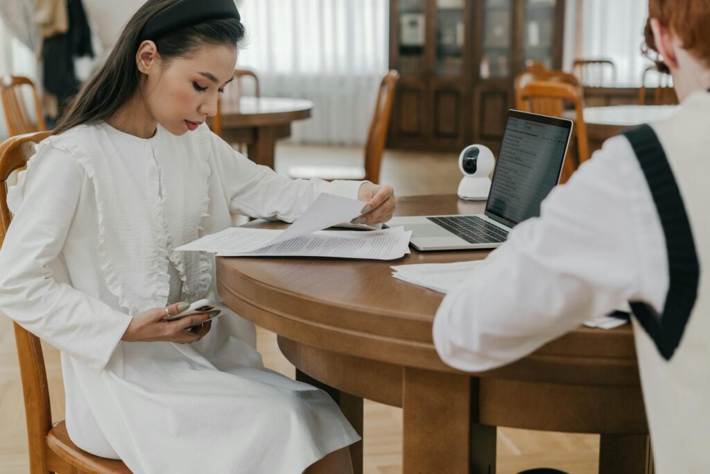 college student sitting at laptop completing financial aid application with documents spread on desk