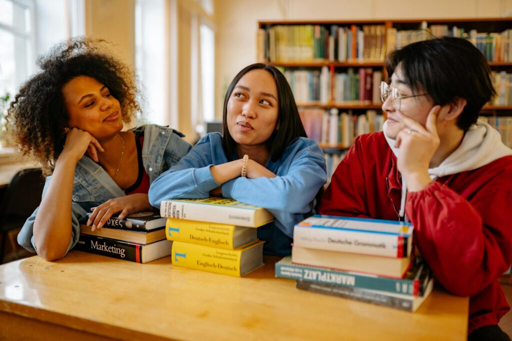 diverse group of college students studying together in university library with scholarship application papers