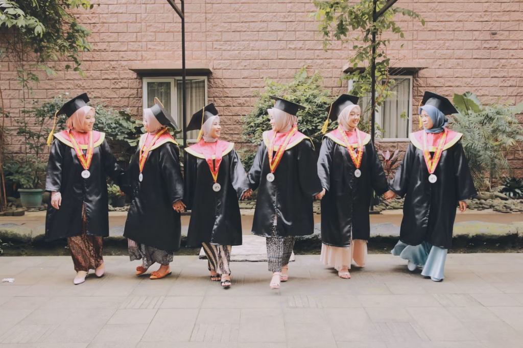 diverse group of women in graduation caps smiling on campus