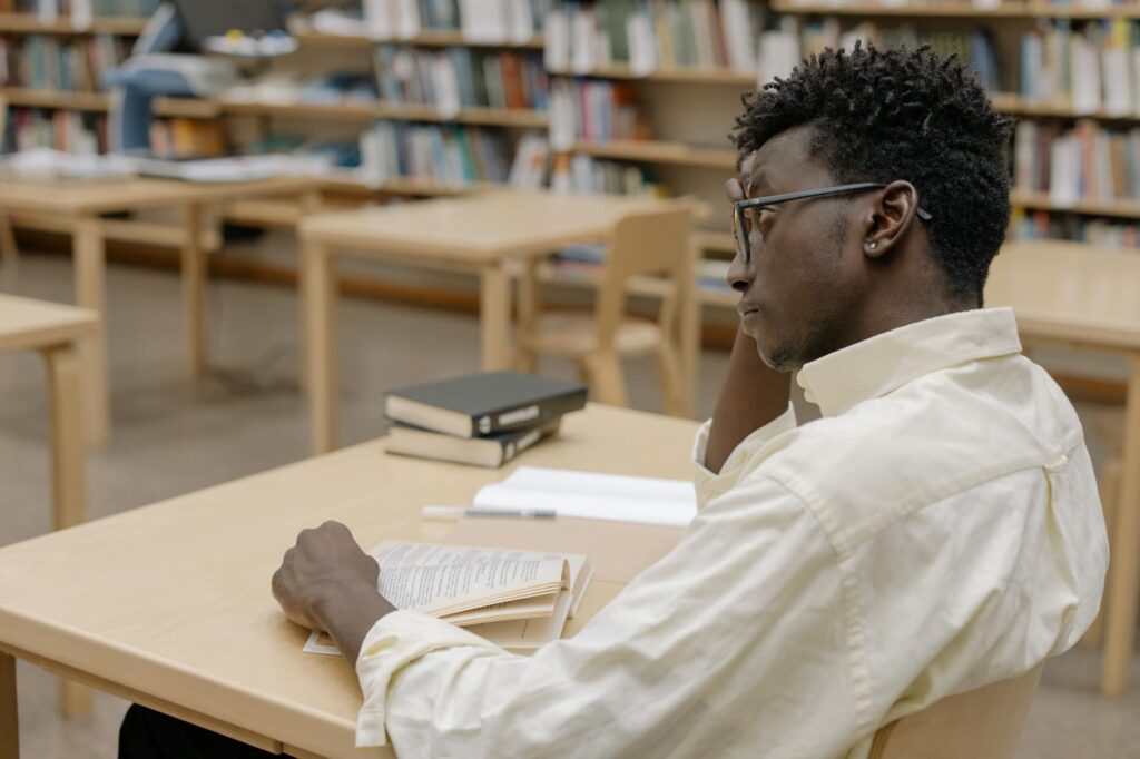 first generation college student studying scholarship application at library desk