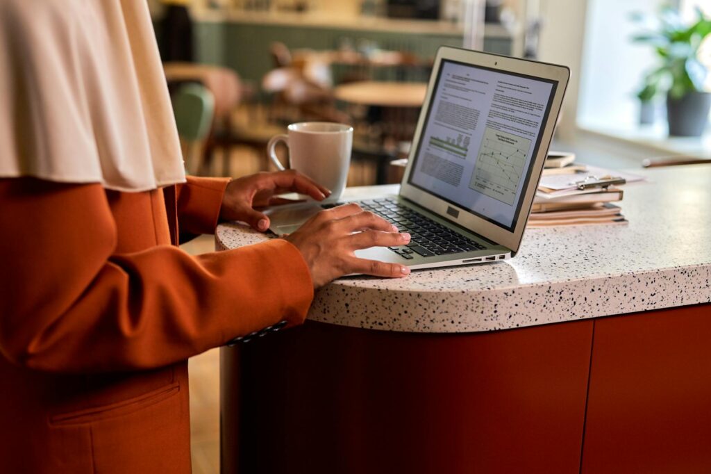 woman researching scholarships on laptop at a bright desk with coffee